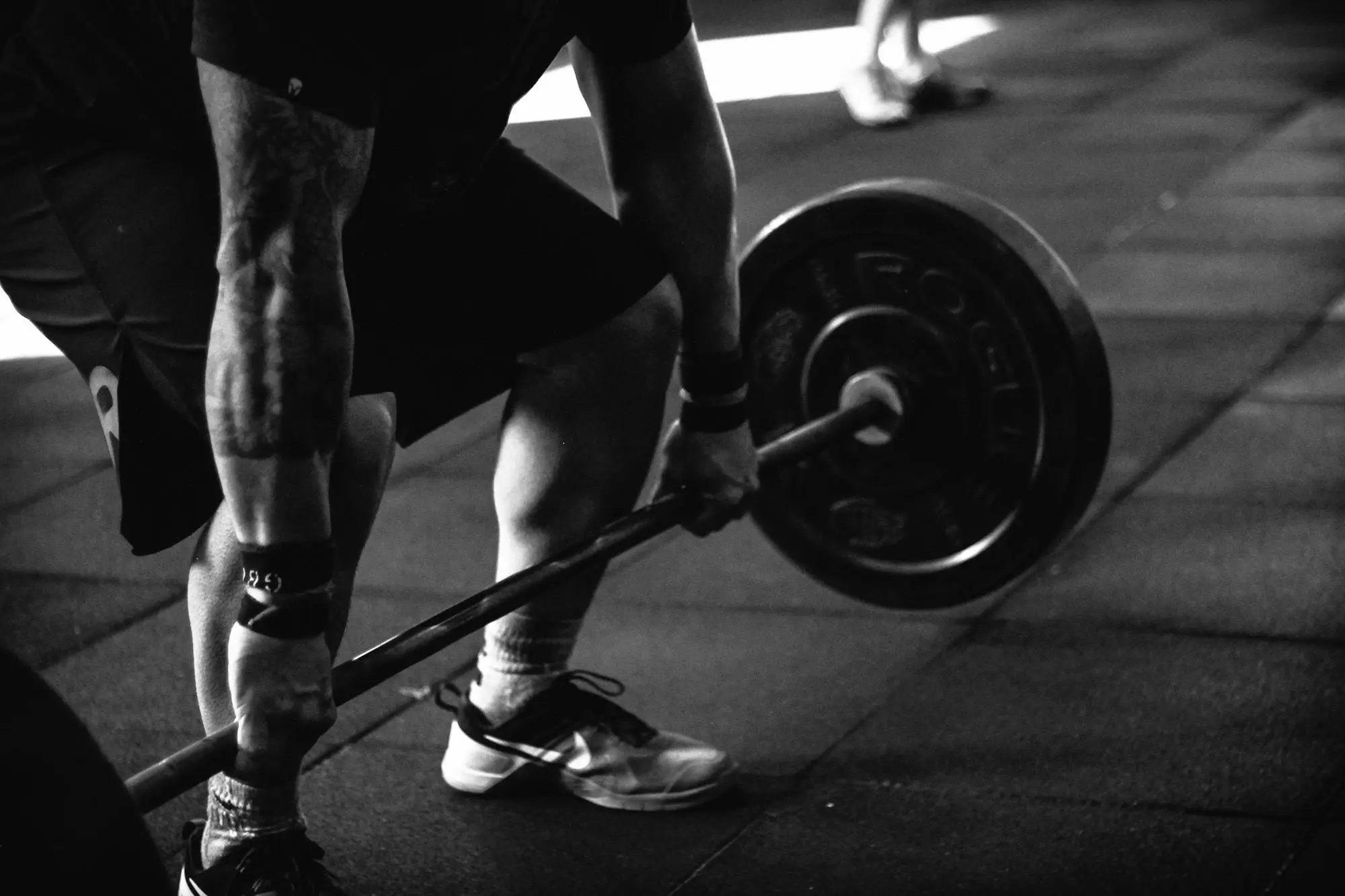 . A shirtless man is lifting a dumbbell, showcasing his strength and focus during a workout session.