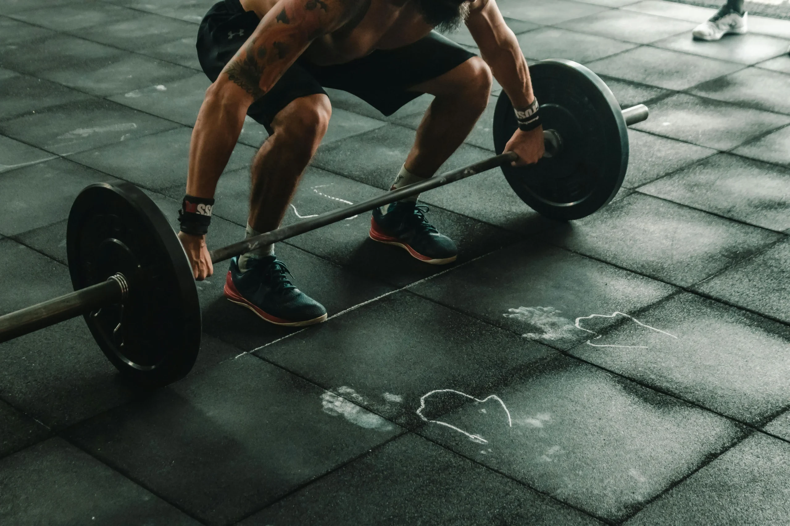 A man performs a squat with a barbell, demonstrating strength training in a fitness environment.